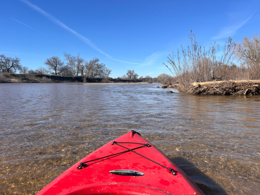 Front of a kayak seen floating through shallow water in the Salinas River