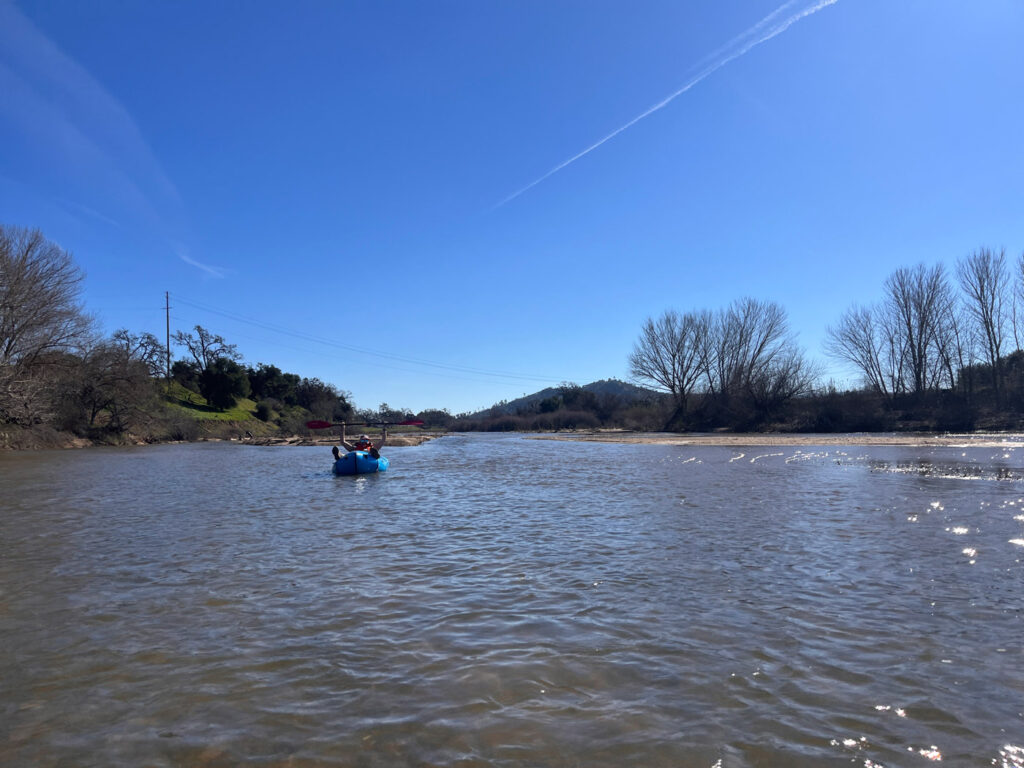 Person holding up paddle in celebration while floating down a river