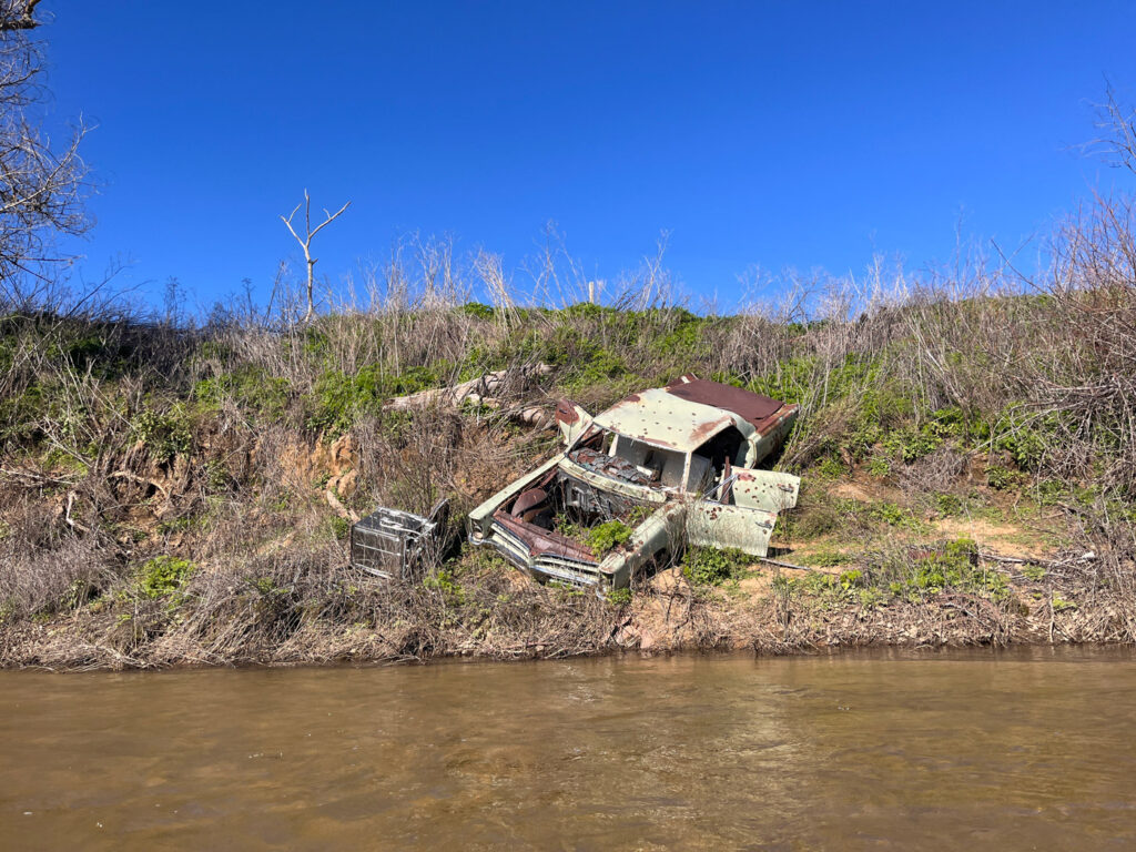 Old abandoned car and appliance on the riverbank